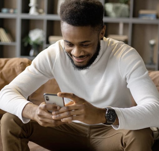 a man is texting with his smartphone in a sofa image